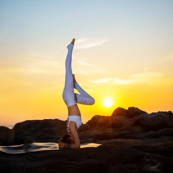Serene woman in a balanced yoga pose against a violet sunset